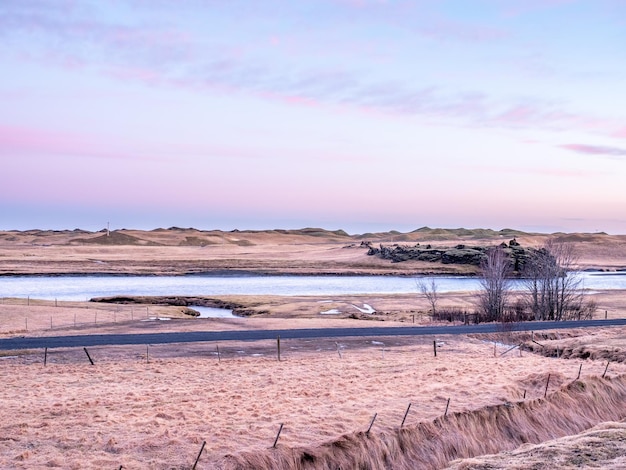 Foto natuurlijk uitzicht op de bergen en het veld in de buitenboerderij onder de schemering van de avondhemel in ijsland tijdens het winterseizoen