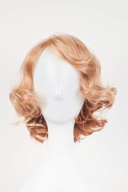 Natuurlijk uitziende blonde lichte pruik op wit mannequin hoofd Korte kapsel op de plastic pruikhouder geïsoleerd op witte achtergrond voorkant