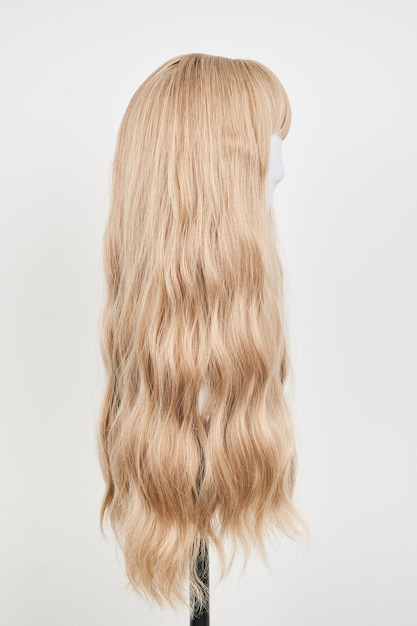 Natuurlijk uitziende blonde pruik op wit mannequin hoofd Lang haar op de plastic pruikhouder geïsoleerd op witte achtergrond zijweergave