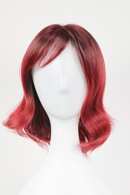 Natuurlijk uitziende rode pruik op wit manekenhoofd Middel lang haar op de plastic pruikhouder geïsoleerd op witte achtergrond voorzijde