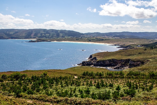 Natuurlijke baai met kalm water omringd door bergen op een zonnige dag in Galicië, Spanje