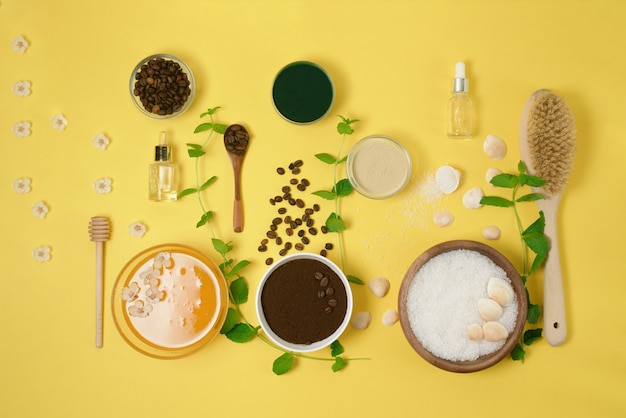 Natuurlijke biologische ingrediënten-zeezout, koffie scrub, honing en een harde body brush op een gele achtergrond. het uitzicht vanaf de top.