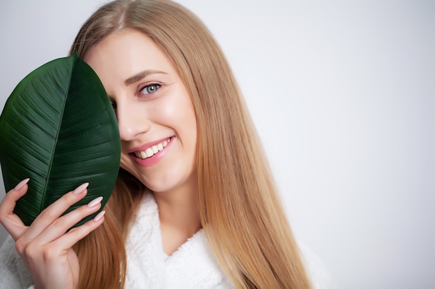 Natuurlijke cosmetica, mooie vrouw gezicht in groene bladeren.