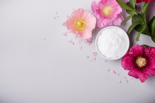 Natuurlijke cosmetica-product op smaak gebracht zeezout en kaasjeskruid bloemen op grijze achtergrond Toned