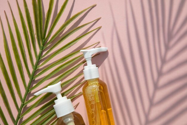 Natuurlijke cosmetische olie in een doorzichtige fles met tropisch blad en schaduw