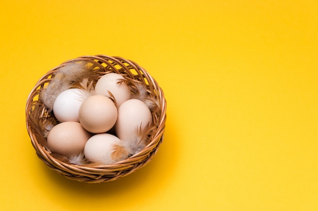 Natuurlijke ecologische eieren en veren in een rieten mand