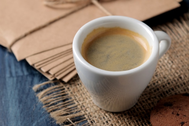 Natuurlijke espressokoffie in een keramische koffiekop en koekjes op een blauwe houten tafel.