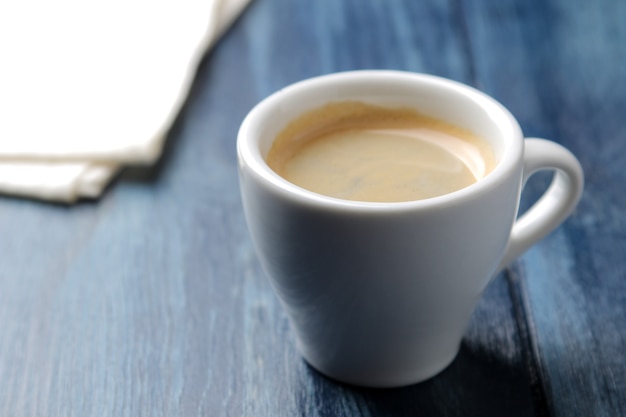 Natuurlijke espressokoffie in een keramische koffiekop op een blauwe houten tafel