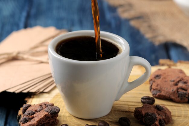 Natuurlijke espressokoffie wordt met Cezve in een kopje op een blauwe houten tafel gegoten