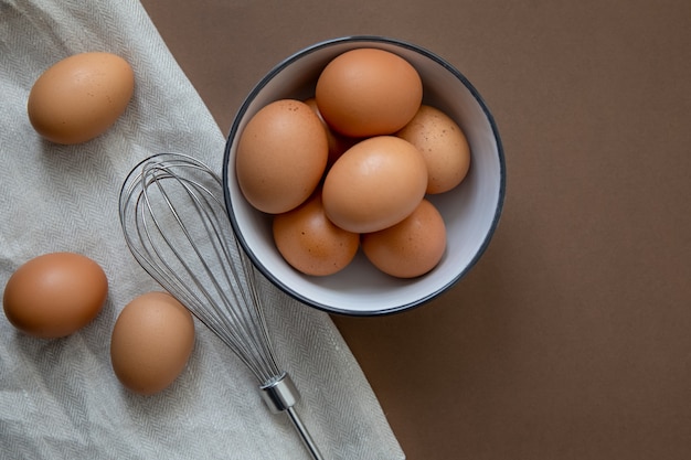 Natuurlijke gezonde voeding en biologisch voedselconcept Rauwe bruine kippeneieren in een bord op een handdoek Bereid je voor op het schudden van de eieren