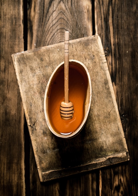 Natuurlijke honing in houten vat met lepel. Op houten achtergrond.