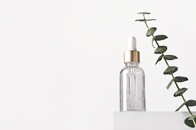 Natuurlijke huidverzorgingsproducten concept Kruiden minerale cosmetica serum hyaluronzuur op wit podium Transparante donkere glazen fles met druppelaar kopie ruimte