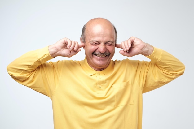 Foto natuurlijke oordopjes gebruiken om geen spoilers te horen knappe, gelukkige volwassen europese man die lacht met gesloten ogen