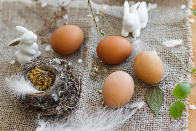 Foto natuurlijke paaseieren konijntjes veren nest en kersen bloeiende tak met bloemblaadjes op rustiek linnen