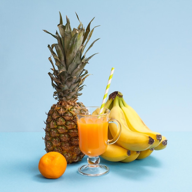 Natuurlijke samenstelling van tropisch fruit Ananas, bananen en mandarijn met glas vruchtensap