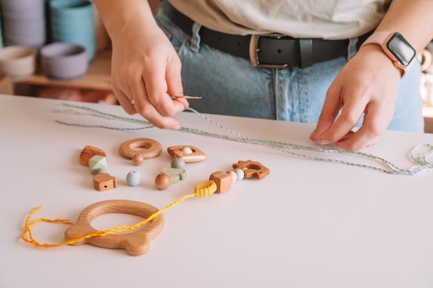 Natuurlijke veilige accessoires van hout op bureau eco-stijl String kralen Ecologische bijtring speelgoed met trinket rammelaar decoratie Handgemaakt werk van speelgoed voor het kauwen van melktanden Stap voor stap Close-up