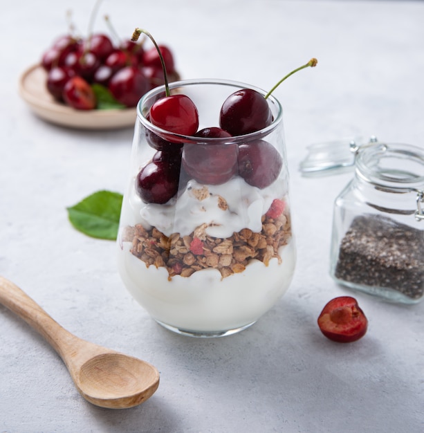 Natuurlijke yoghurt met granola chiazaad en kersen in glas