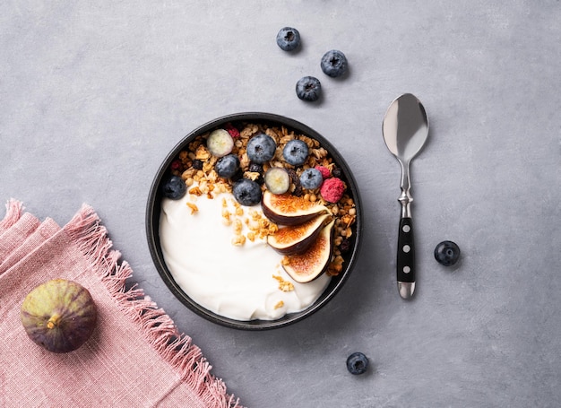 Natuurlijke yoghurt met mueslibessen en vijgen in een kom op een blauwe achtergrond Gezond en voedzaam ontbijt Dieetvoeding