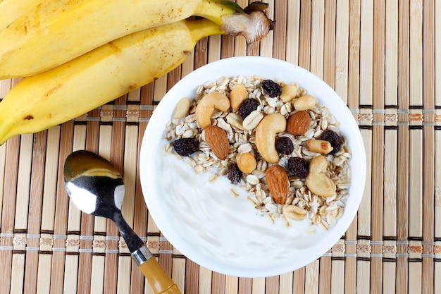 Natuurlijke yoghurt met zelfgemaakte granola en noten in een keramische kom op een tafeltop