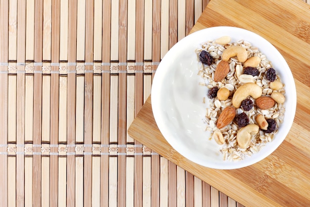 Foto natuurlijke yoghurt met zelfgemaakte granola en noten in een keramische kom op een tafeltop