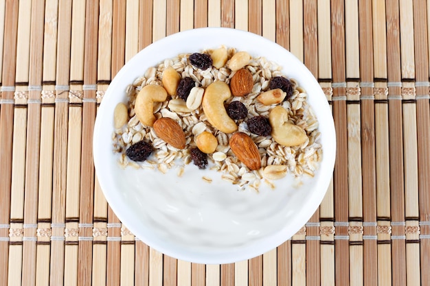 Foto natuurlijke yoghurt met zelfgemaakte granola en noten in een keramische kom op een tafeltop