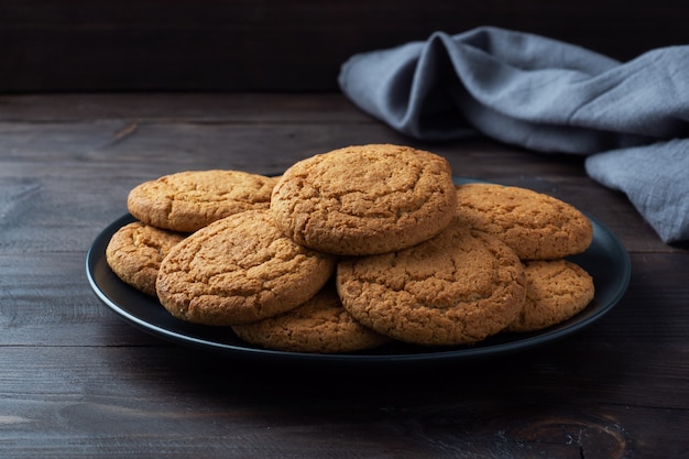 Natuurlijke zelfgemaakte havermoutkoekjes op een bord, donkere houten achtergrond, kopieerruimte.