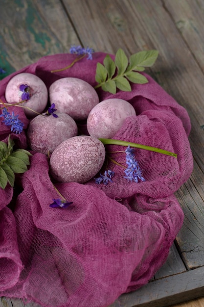 Foto natuurtje van prachtige textureerde paarse eieren op paarse gaas met voorjaarsbloemen