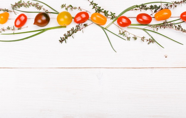 Natuurvoeding achtergrond. studiofoto van verschillende groenten veelkleurige tomaten en kruiden, tijm, groene uien op witte houten tafel. product met hoge resolutie. gezond voedselconcept