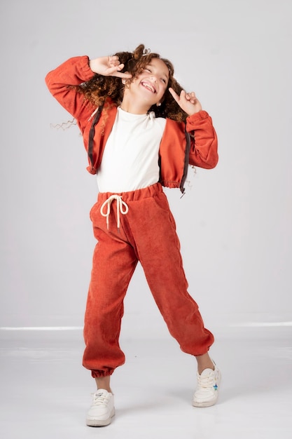 Naughty little girl with curly hair in pajamas having fun and laughing.