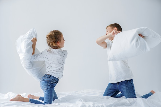 Naughty twins friendly fighting with pillows on the bed
