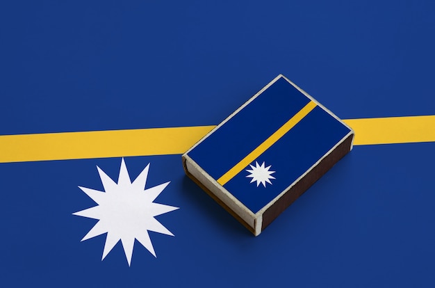 Photo nauru flag  is pictured on a matchbox that lies on a large flag