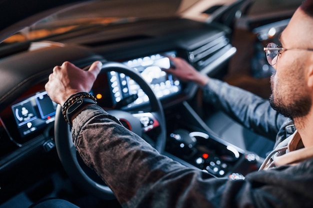 Navigatiescherm gebruiken Knappe ongeschoren man in modieuze kleding die in zijn auto rijdt