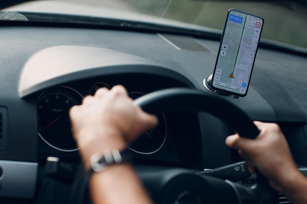 Navigatore nel pendolare del trasporto di veicoli in auto autista che utilizza l'app del navigatore del telefono cellulare durante la guida dell'auto