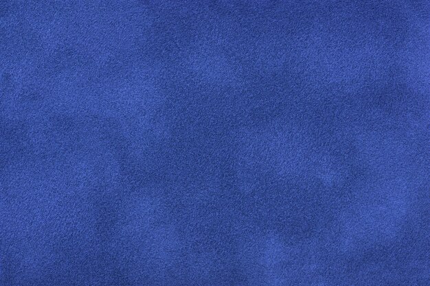 Photo navy blue matte background of suede fabric, closeup. velvet texture of seamless sapphire textile, macro. structure of indigo felt canvas backdrop.