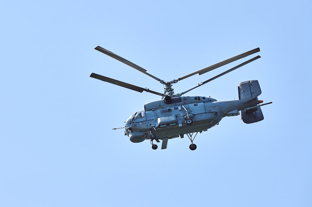 Navy helicopter flying against bright blue sky background, copy space. One military anti-submarine warfare helicopter demonstrating submarine search, side view