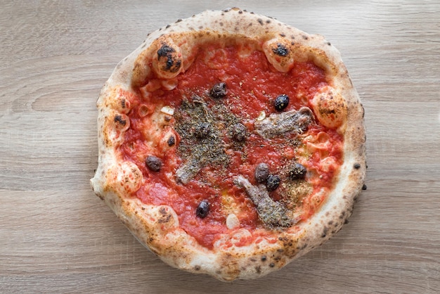 Neapolitan pizza with anchovies tomato sauce black olives fermented dough baked crusts top view