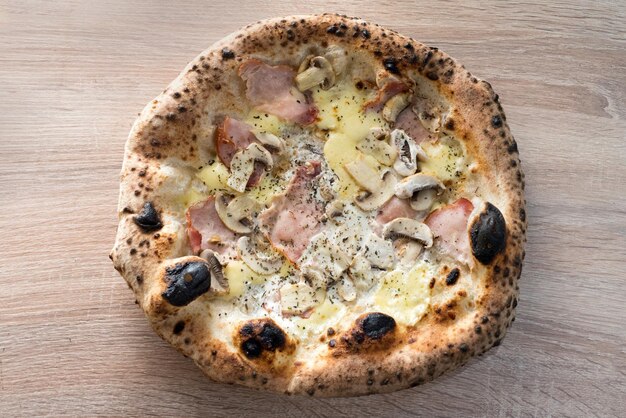 Foto pizza napoletana con funghi di prosciutto e formaggio ai bordi cotti in un forno a legna
