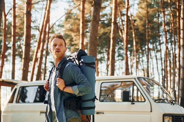 Photo near car and camp man is traveling alone in the forest at daytime at summer