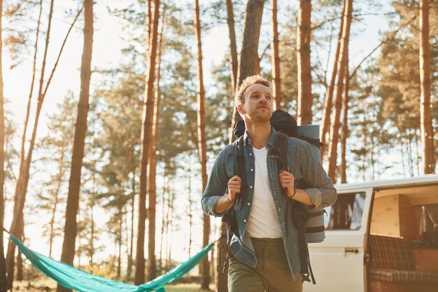 車とキャンプの近く夏の昼間、男は森の中を一人で旅行しています