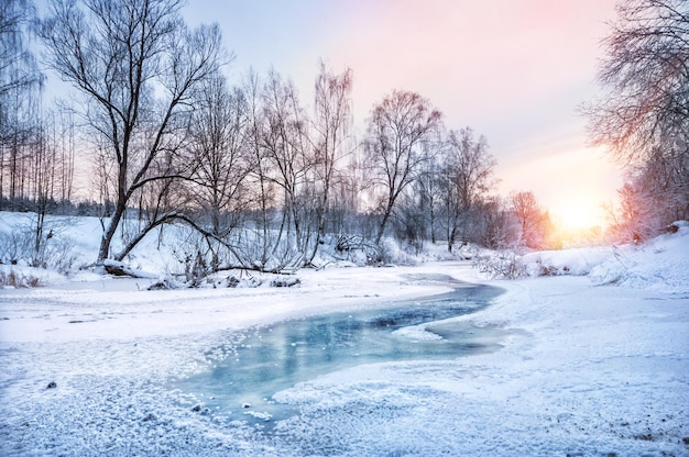 Near Moscow river Vorya covered with ice with dark thawed patches in a snowcovered forest