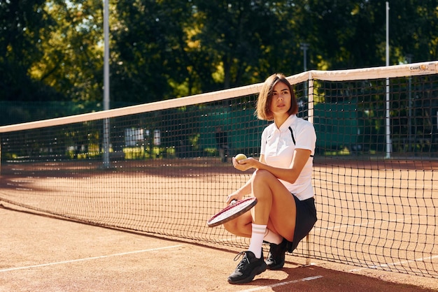 Near the net Female tennis player is on the court at daytime