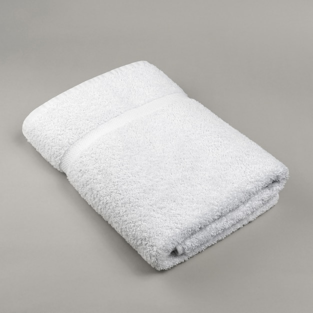 Photo neat folded fluffy fresh white towel on gray surface