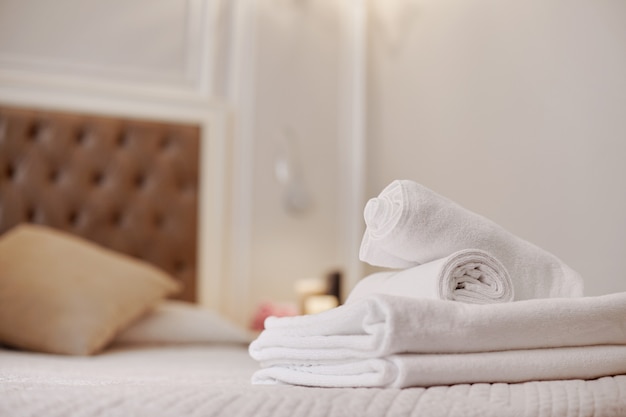 Neatly folded white towels lie on the bed in the room