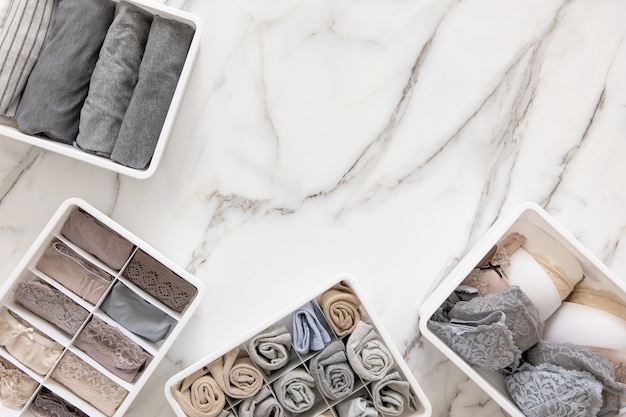 Neatly and tidy folded lingeries in organizer drawer divider on white marble