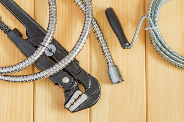 Necessary set of tools and hoses for master plumber on wooden boards