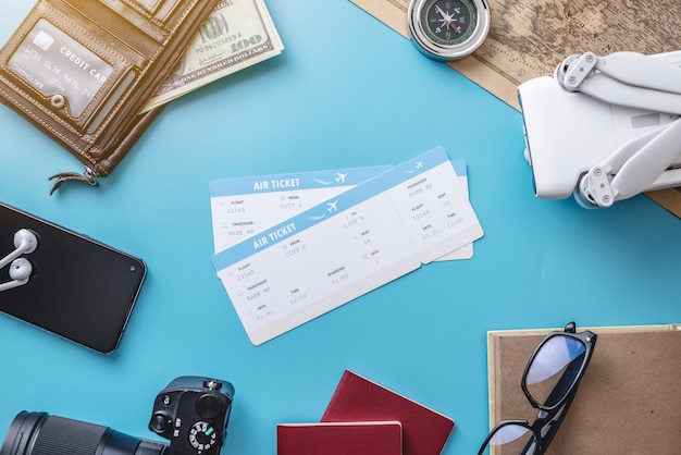 Necessary things for the flight on vacation. Plane tickets, passport, phone, credit card, drone quadcopter, camera on a blue background