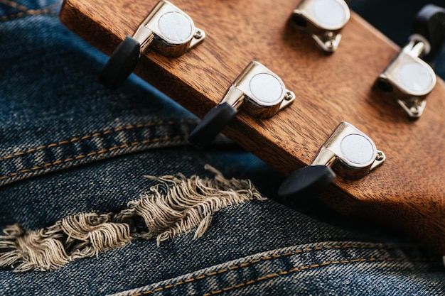 Neck of acoustic guitar is closeup on denim fabric Hipster culture Background Musical instrument