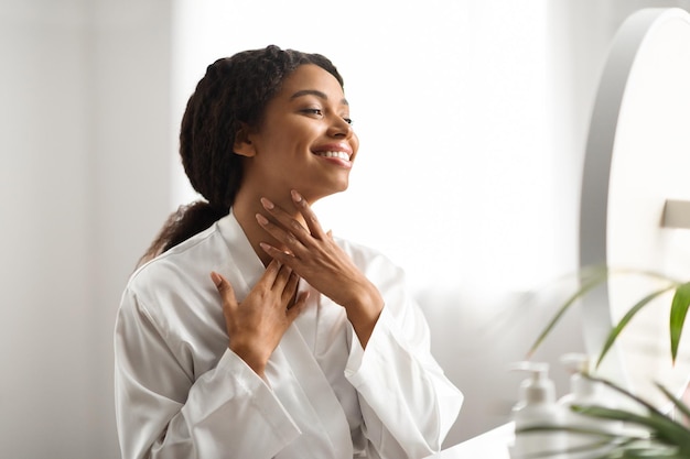 Neck lift concept smiling african american woman touching her soft smooth skin