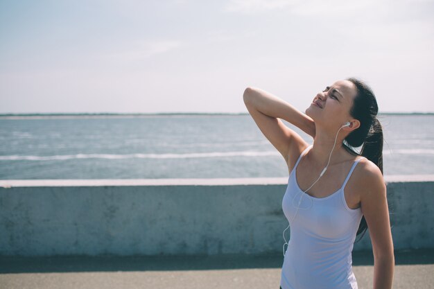 Neck pain during training. Athlete running Caucasian black hair woman runner with sport injury and touching upper back muscles outside after exercise workout in summer