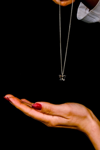 Photo a necklace with a diamond on it is being held up by a hand